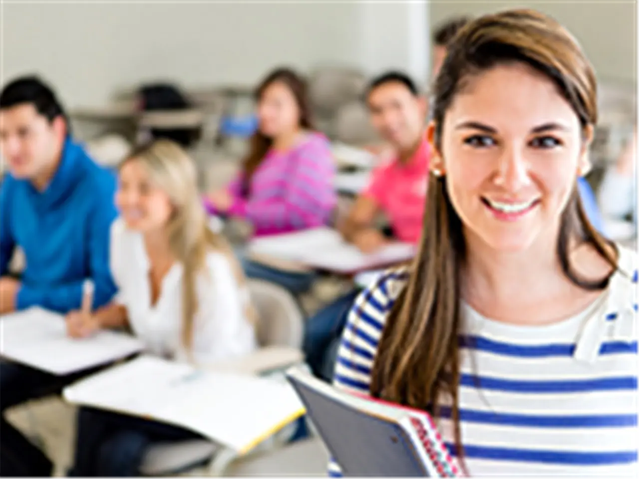 Female college student in a classroom holding a notebook?
